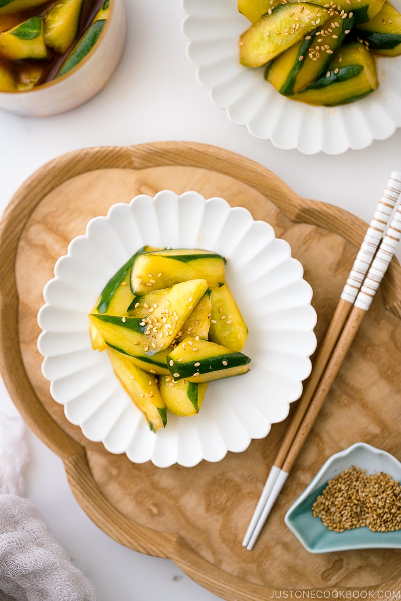 A white plate containing Spicy Japanese Pickled Cucumbers sprinkled with white sesame seeds.