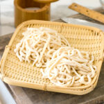 A bamboo basket containing homemade udon noodles.