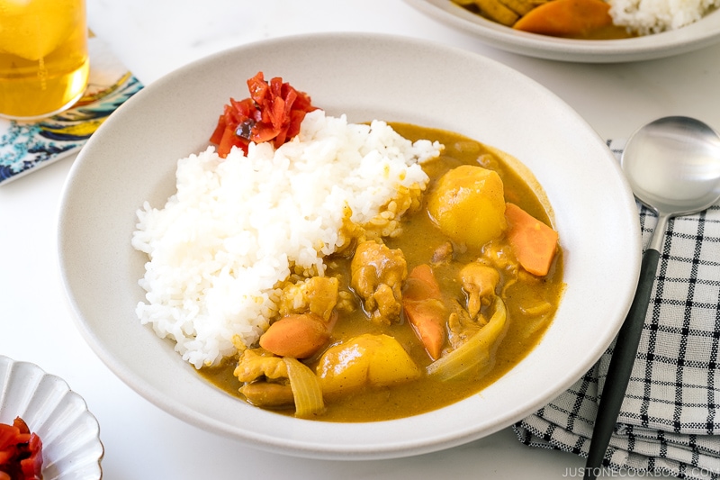 A ceramic bowl containing Japanese Chicken Curry along with steamed rice and fukujinzuke pickles.