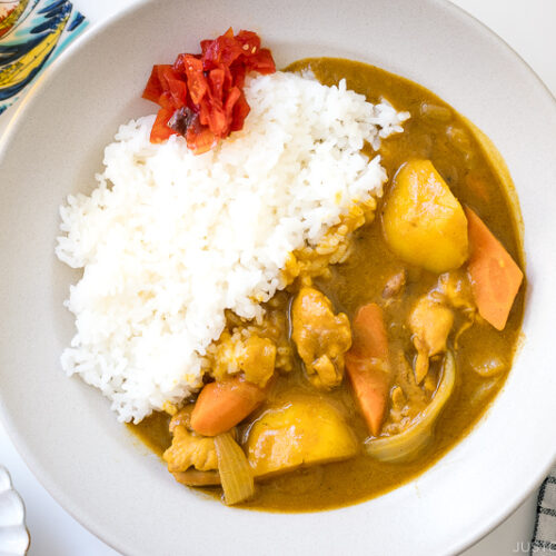 A ceramic bowl containing Japanese Chicken Curry along with steamed rice and fukujinzuke pickles.