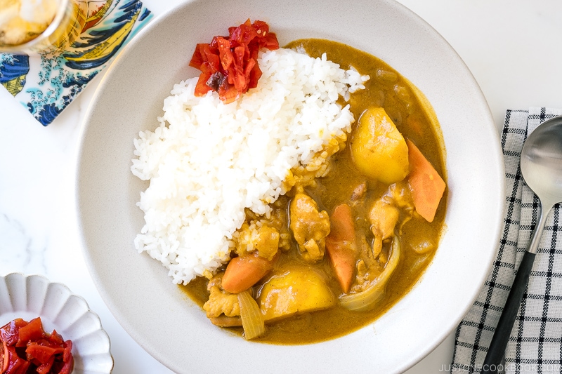 A ceramic bowl containing Japanese Chicken Curry along with steamed rice and fukujinzuke pickles.