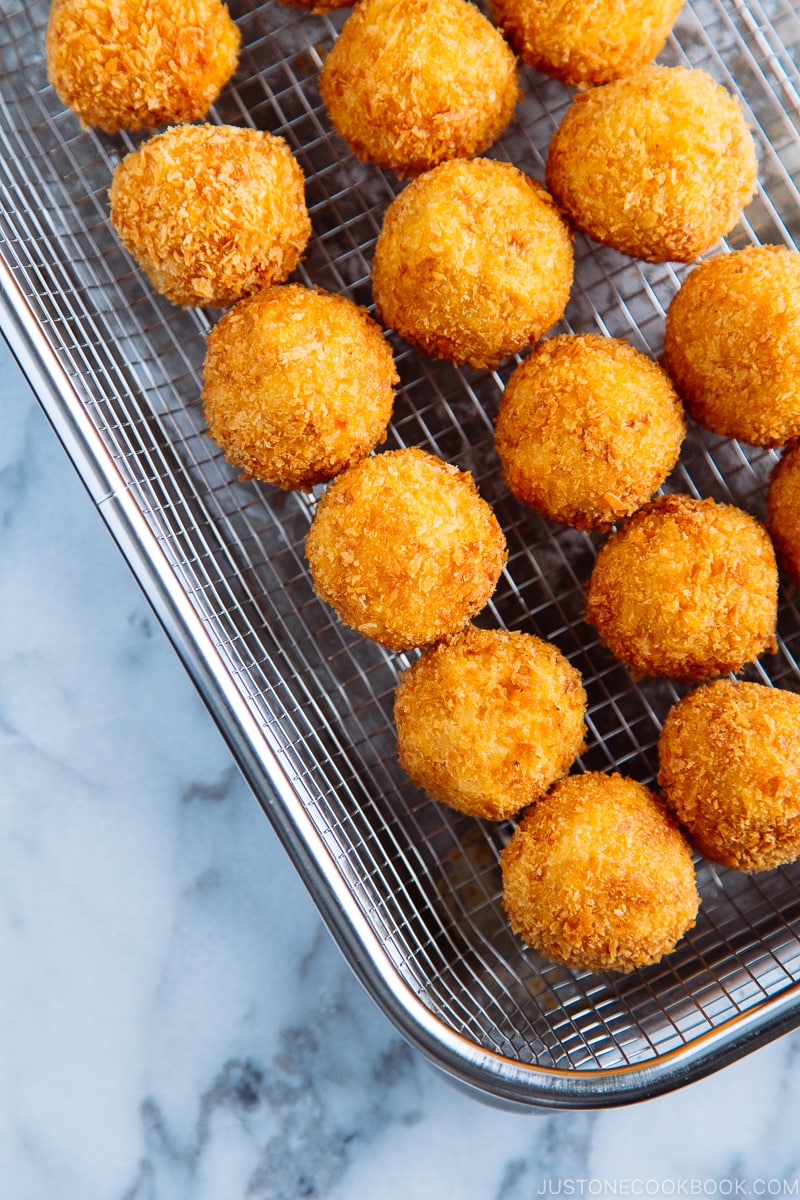 A stainless steel wire rack containing round Kabocha Croquettes (Korokke).