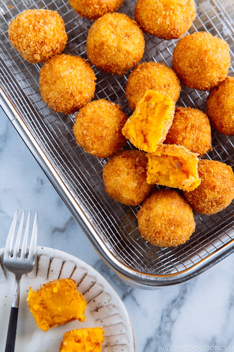 A stainless steel wire rack containing round Kabocha Croquettes (Korokke).