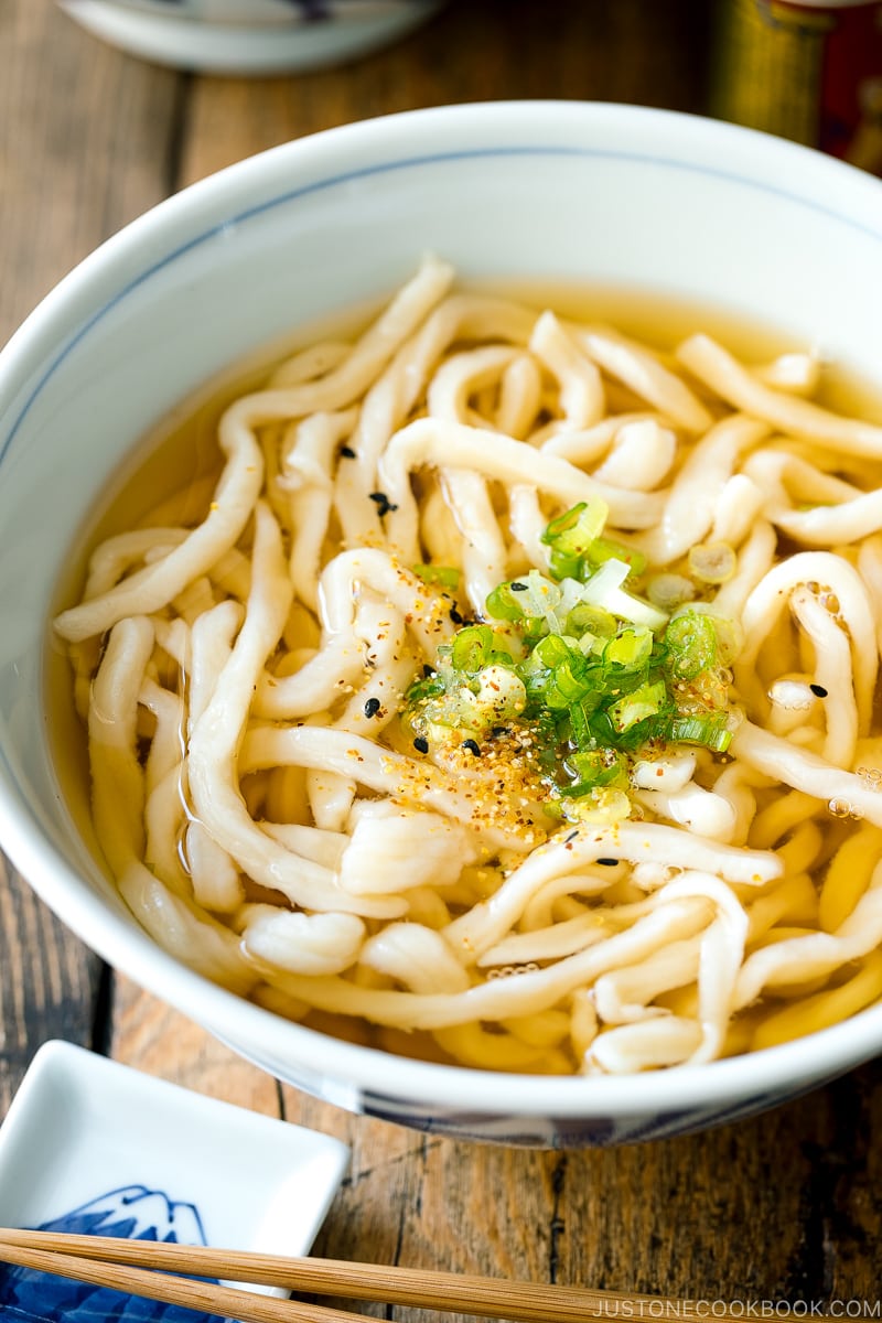 A Japanese bowl containing fresh homemade udon noodles in clear soy based dashi broth.