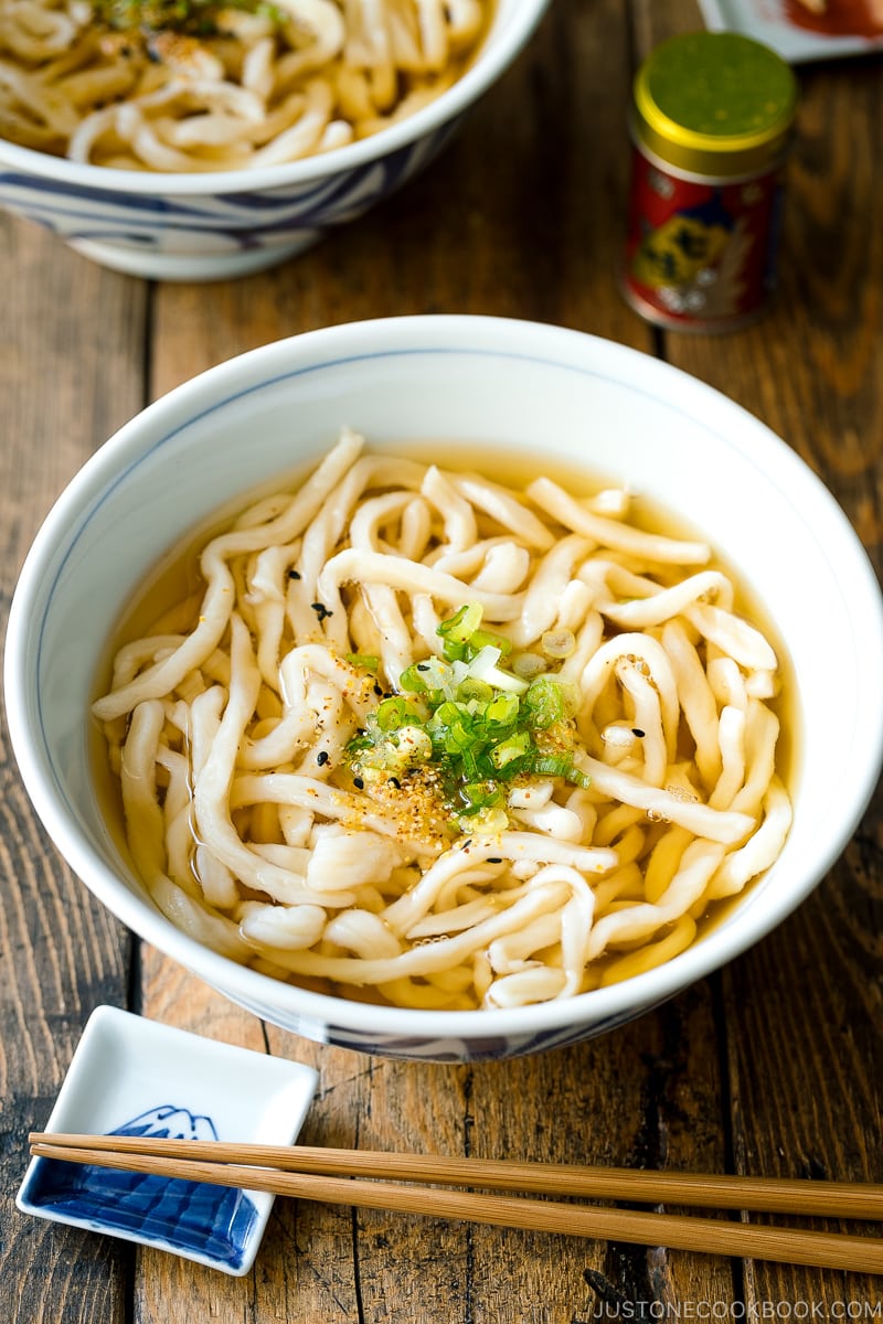 A Japanese bowl containing fresh homemade udon noodles in clear soy based dashi broth.