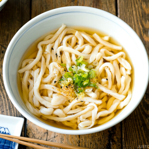 A Japanese bowl containing fresh homemade udon noodles in clear soy based dashi broth.