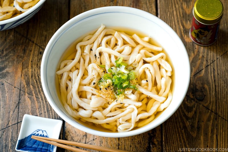 A Japanese bowl containing fresh homemade udon noodles in clear soy based dashi broth.