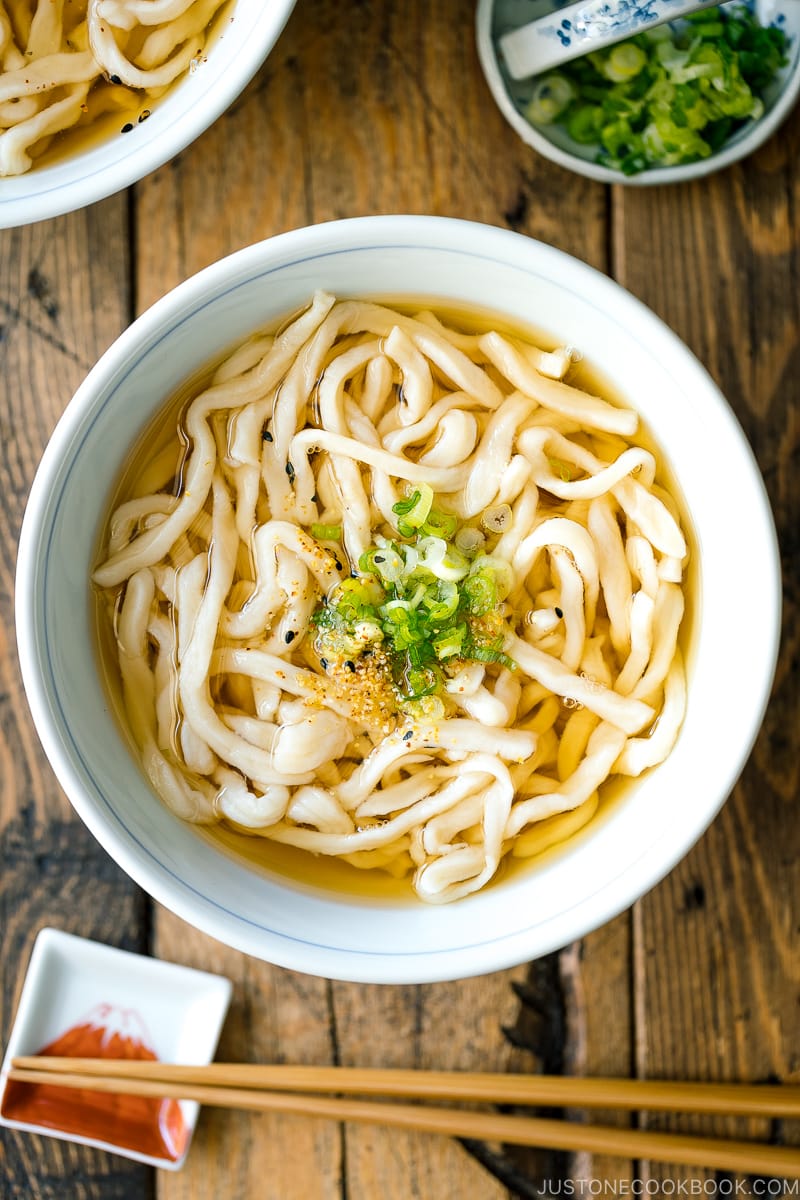 A Japanese bowl containing fresh homemade udon noodles in clear soy based dashi broth.