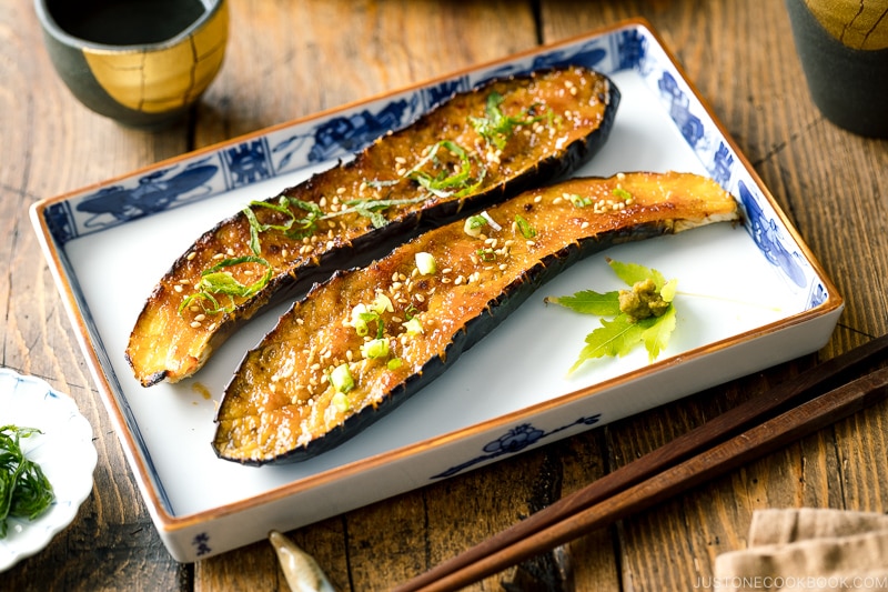 A square plate containing Miso Glazed Eggplant garnished with yuzu kosho.