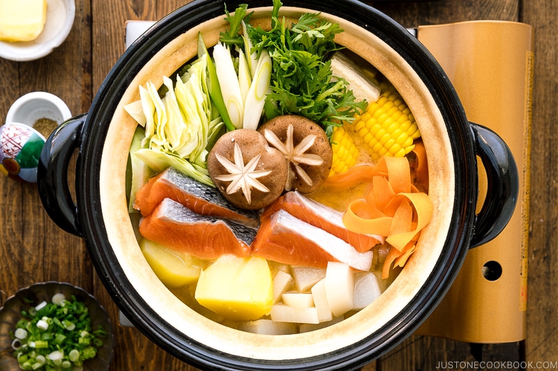 A Japanese donabe clay pot containing salmon, potato, daikon, corn, cabbage simmered in miso-based soup.