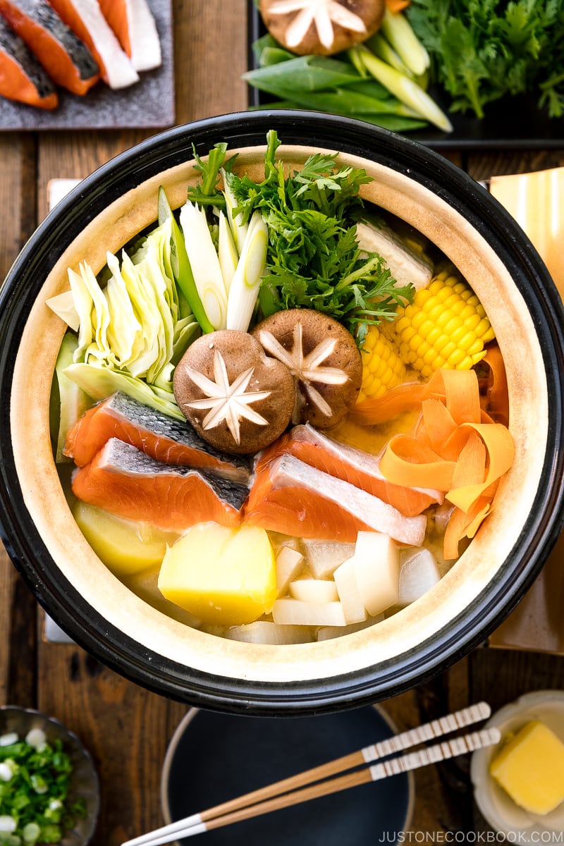 A Japanese donabe clay pot containing salmon, potato, daikon, corn, cabbage simmered in miso-based soup.