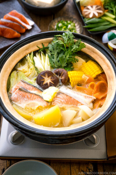 A Japanese donabe clay pot containing salmon, potato, daikon, corn, cabbage simmered in miso-based soup.