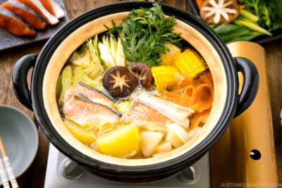 A Japanese donabe clay pot containing salmon, potato, daikon, corn, cabbage simmered in miso-based soup.