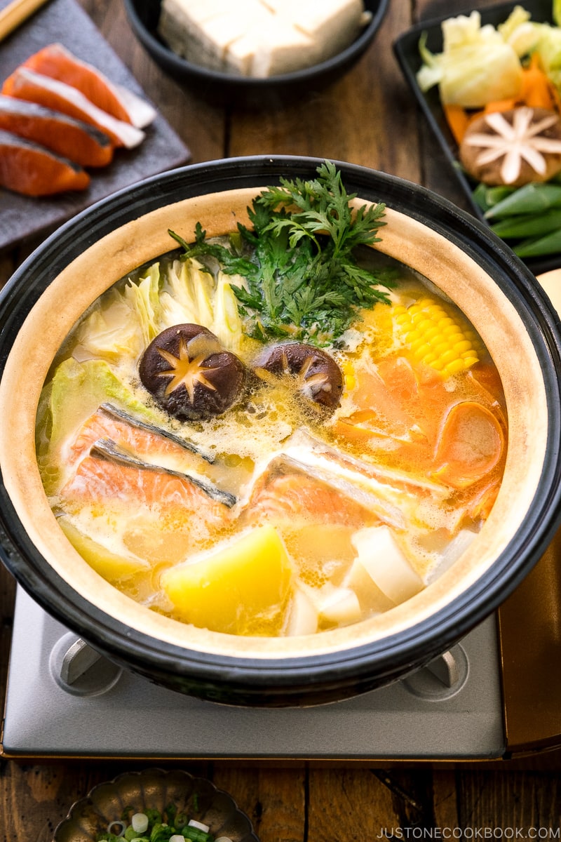 A Japanese donabe clay pot containing salmon, potato, daikon, corn, cabbage simmered in miso-based soup.