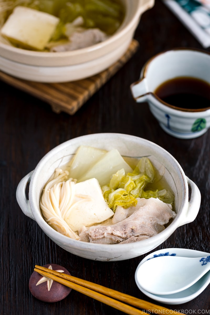 A donabe containing pork, cabbage, tofu, and mushrooms in a kombu broth.