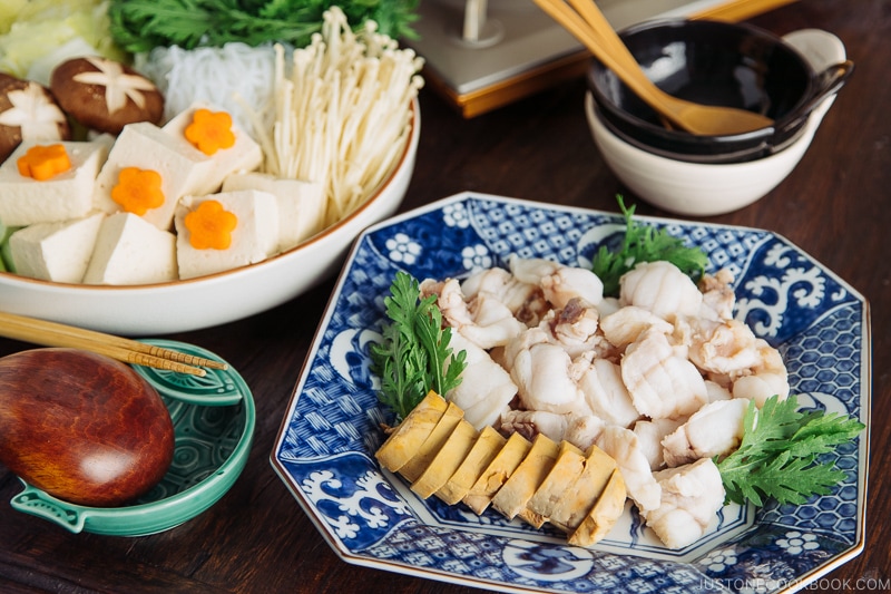 A donabe set over the portable gas stove and platters of monkfish and vegetables.