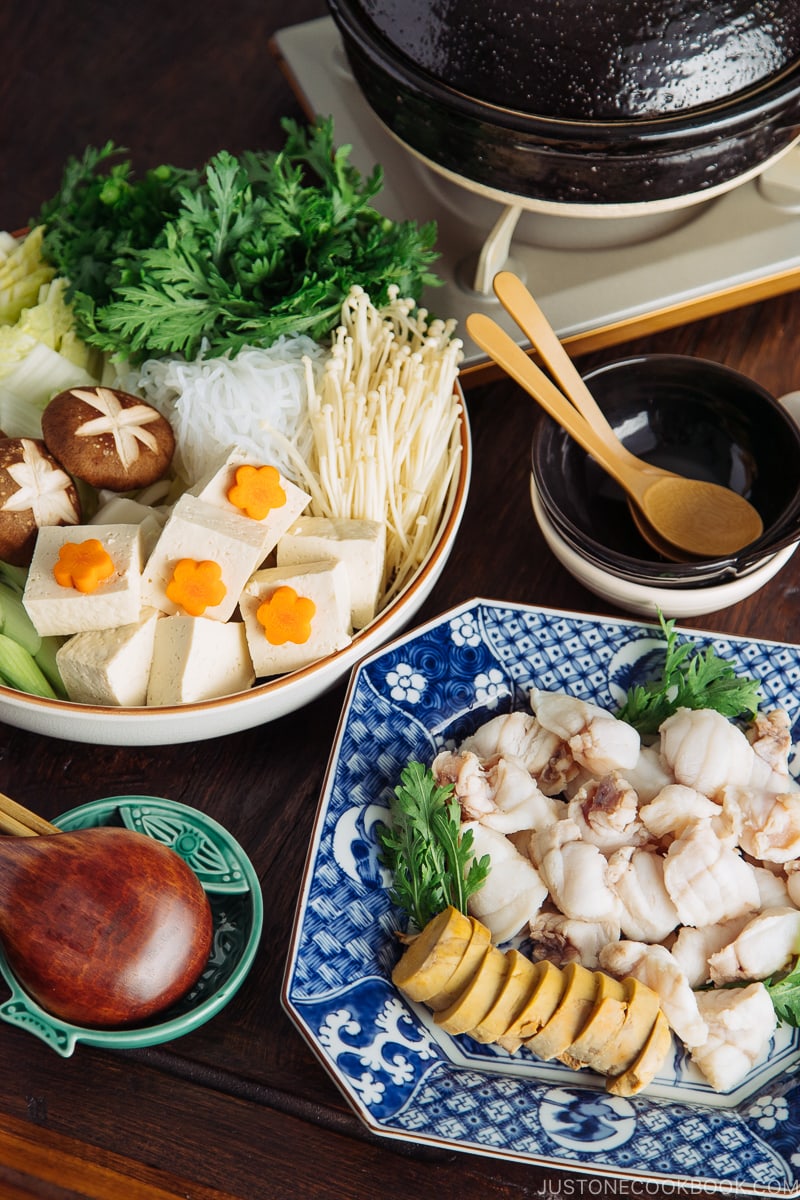 A donabe set over the portable gas stove and platters of monkfish and vegetables.