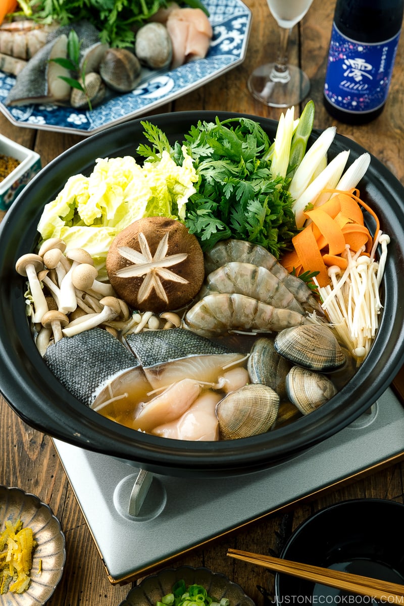 A donabe (earthenware hot pot) containing meat, seafood, and vegetables.