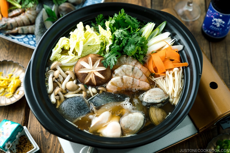 A donabe (earthenware hot pot) containing meat, seafood, and vegetables.