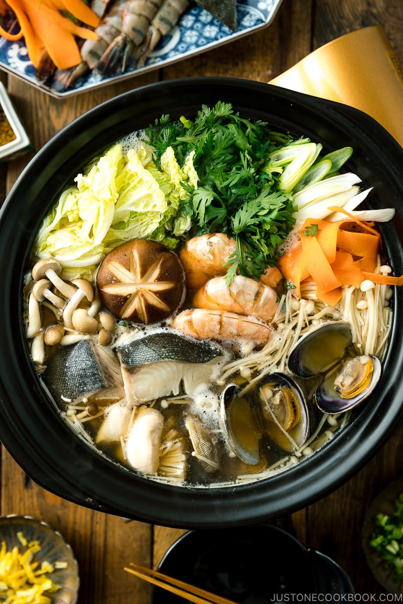 A donabe (earthenware hot pot) containing meat, seafood, and vegetables.