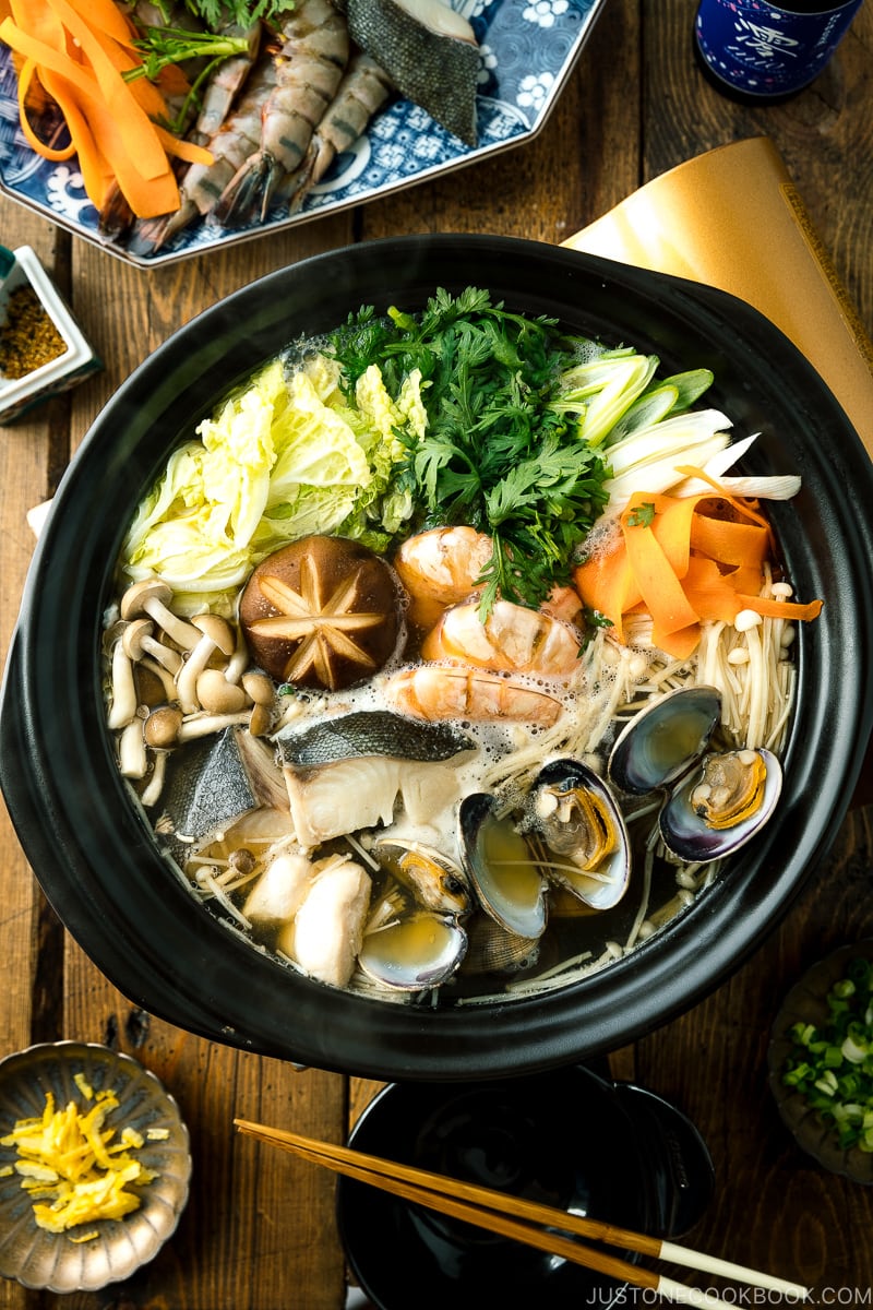 A donabe (earthenware hot pot) containing meat, seafood, and vegetables.