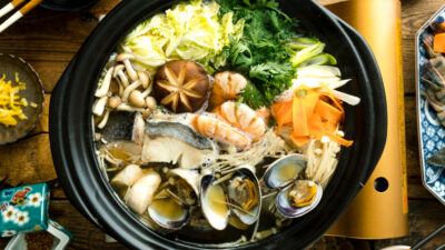 A donabe (earthenware hot pot) containing meat, seafood, and vegetables.