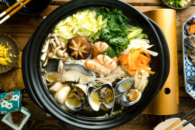 A donabe (earthenware hot pot) containing meat, seafood, and vegetables.