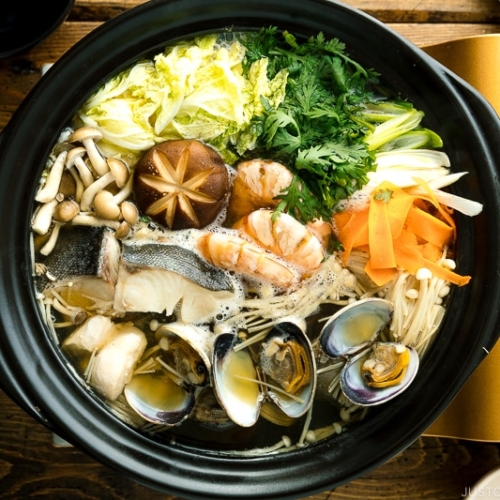 A donabe (earthenware hot pot) containing meat, seafood, and vegetables.