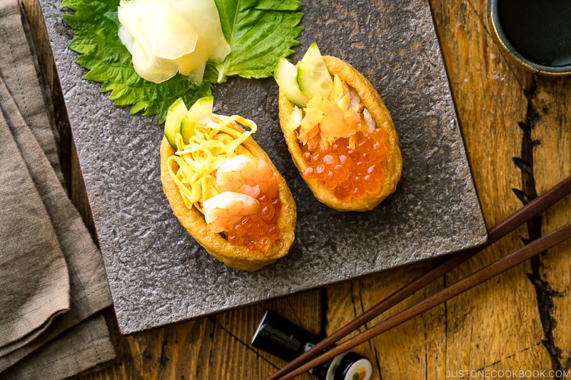 A Japanese plate containing inari sushi garnished with sushi ginger.