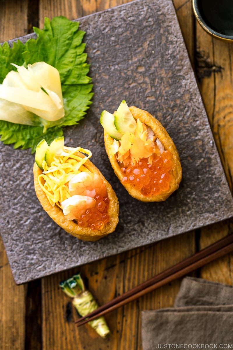A Japanese plate containing inari sushi garnished with sushi ginger.