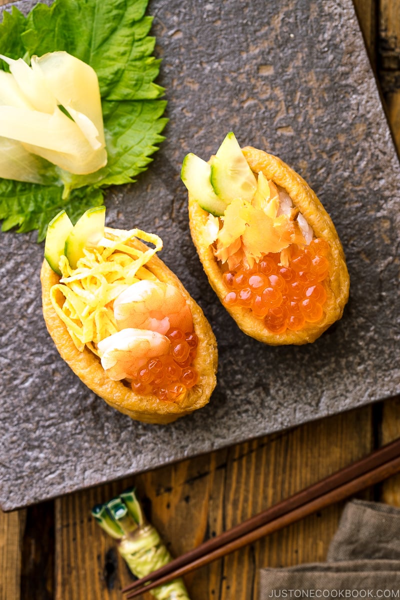 A Japanese plate containing inari sushi garnished with sushi ginger.