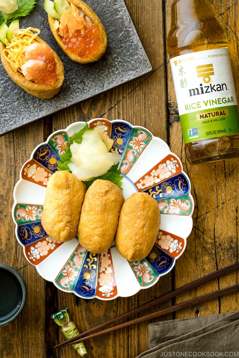 A Japanese plate containing inari sushi garnished with sushi ginger.