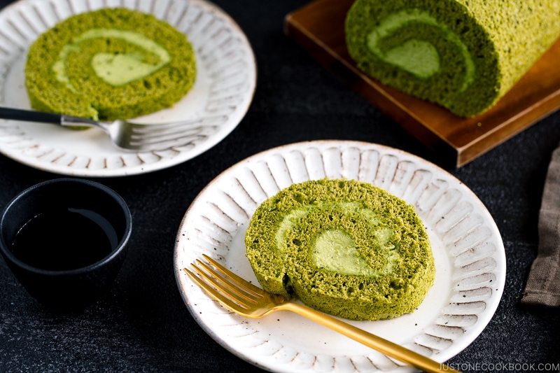 White ceramic plates containing a slice of matcha Swiss roll.