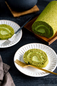 White ceramic plates containing a slice of matcha Swiss roll.