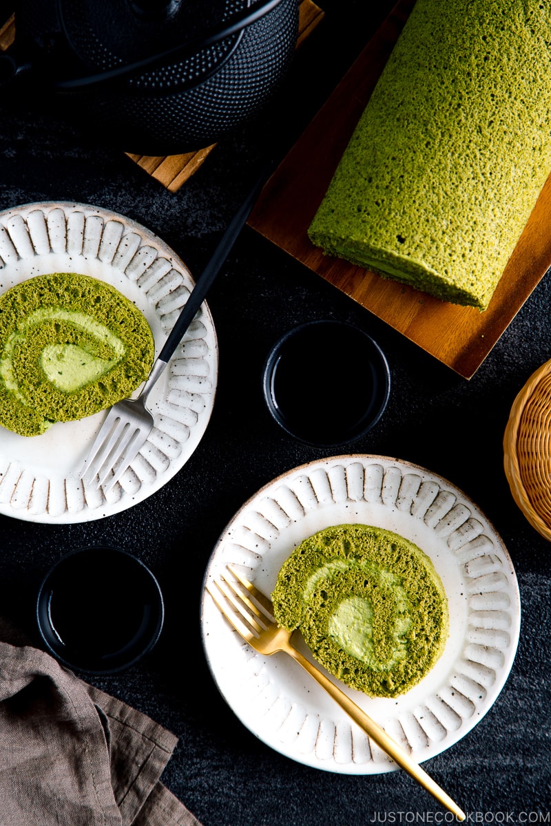 White ceramic plates containing a slice of matcha Swiss roll.