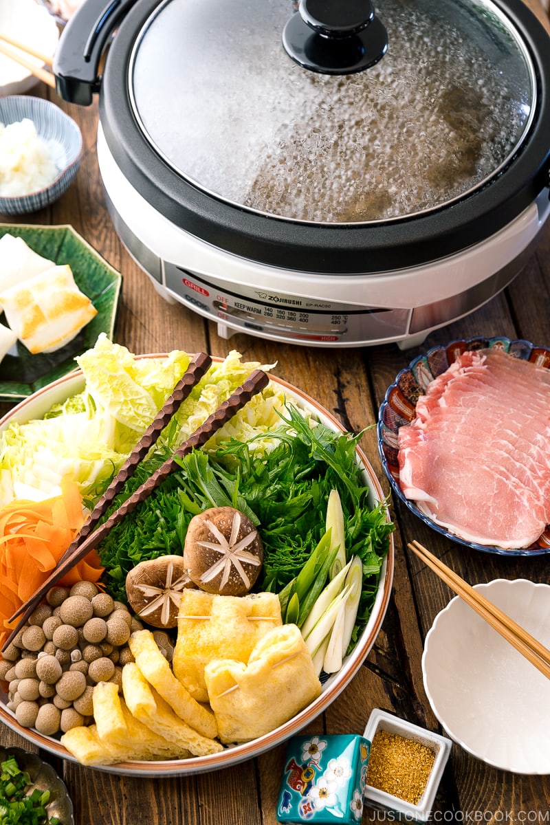 Hot pot ingredients are placed on several platters next to the Zojirushi electric hot pot.