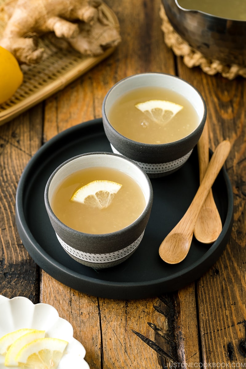 Ceramic cups containing Japanese Ginger Tea (Shogayu) garnished with a slice of lemon.