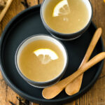 Ceramic cups containing Japanese Ginger Tea (Shogayu) garnished with a slice of lemon.