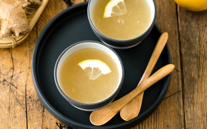 Ceramic cups containing Japanese Ginger Tea (Shogayu) garnished with a slice of lemon.