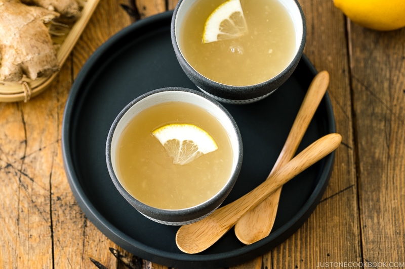 Ceramic cups containing Japanese Ginger Tea (Shogayu) garnished with a slice of lemon.