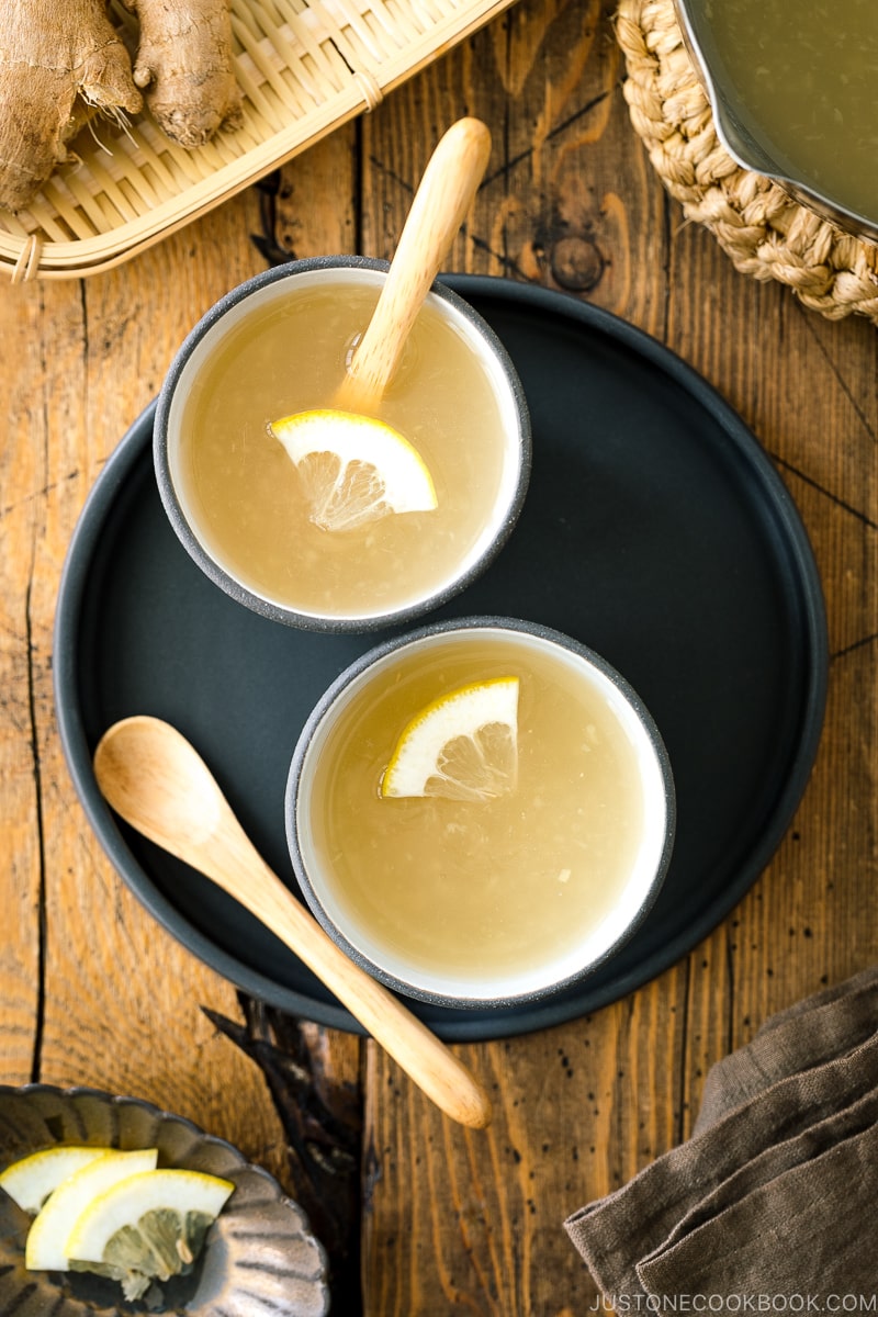 Ceramic cups containing Japanese Ginger Tea (Shogayu) garnished with a slice of lemon.