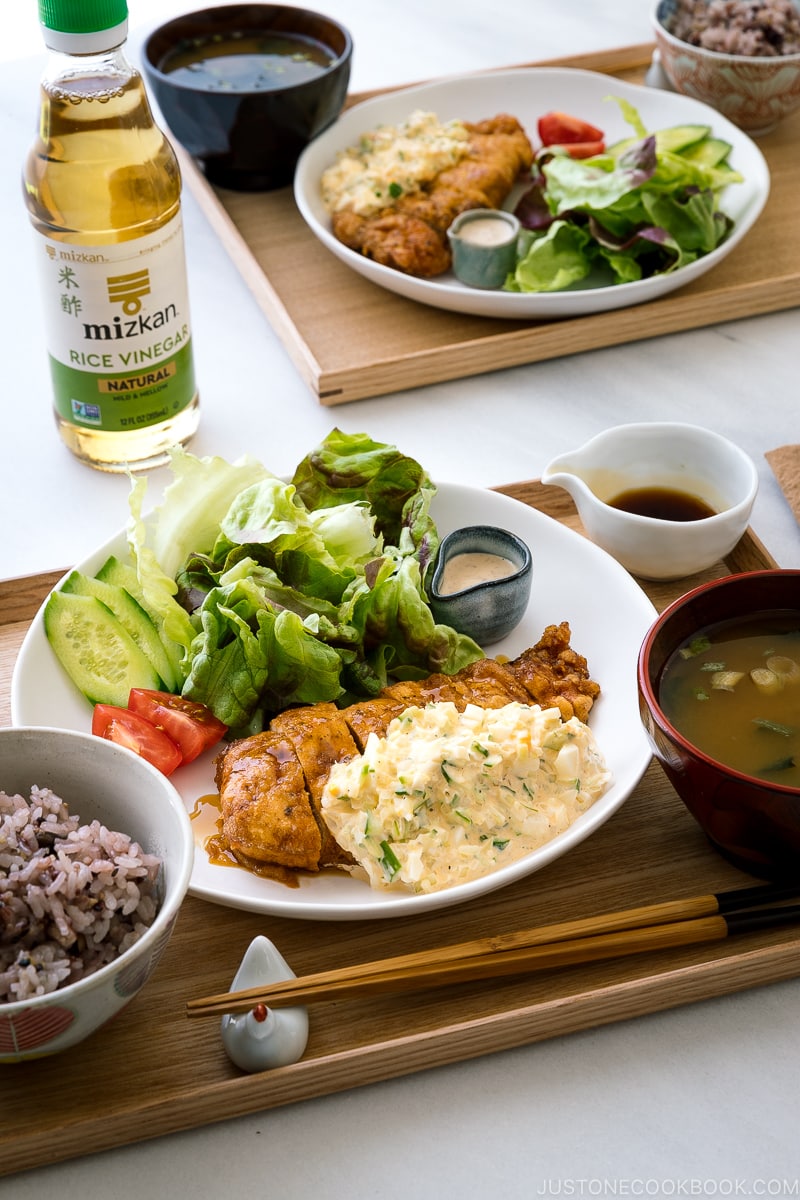 A white plate containing crispy chicken dressed with a tangy sauce and served with homemade tartar sauce.