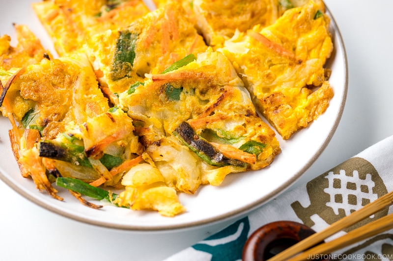 A white plate containing gluten free Korean veggie pancake.