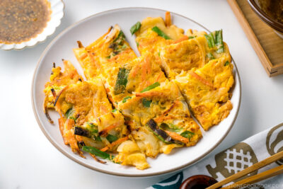 A white plate containing gluten free Korean veggie pancake.