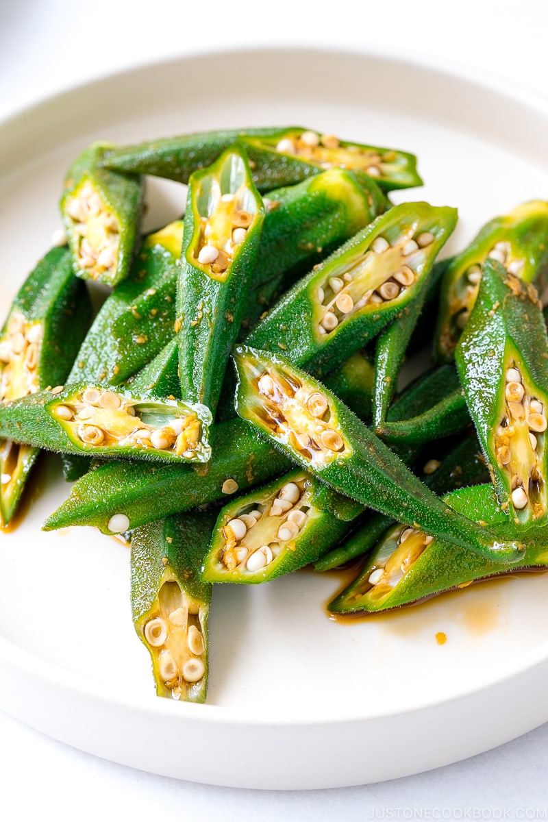 A white plate containing okra with ginger soy sauce.