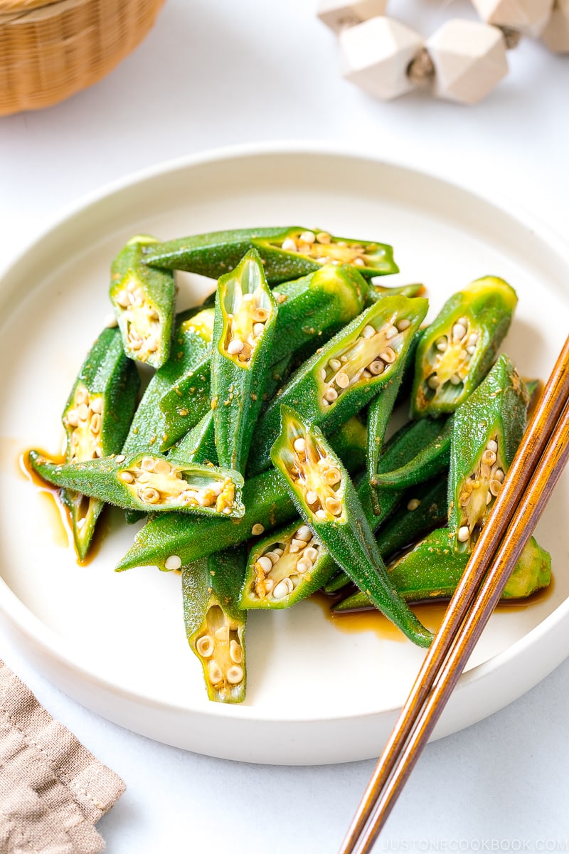 A white plate containing okra with ginger soy sauce.