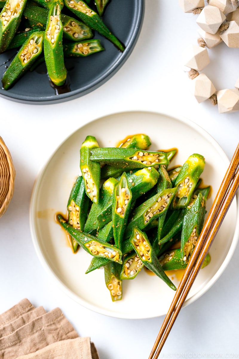 A white plate containing okra with ginger soy sauce.