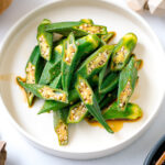 A white plate containing okra with ginger soy sauce.