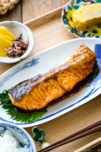 A plate containing Teriyaki Salmon served with steamed rice and miso soup.