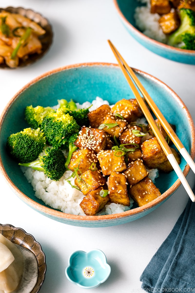 A taquoise bowl containing teriyaki tofu and broccoli over steamed rice.